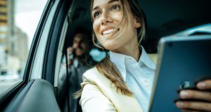 Businesspeople carpooling to work as passengers and using their commuting time to talk on the phone, read…